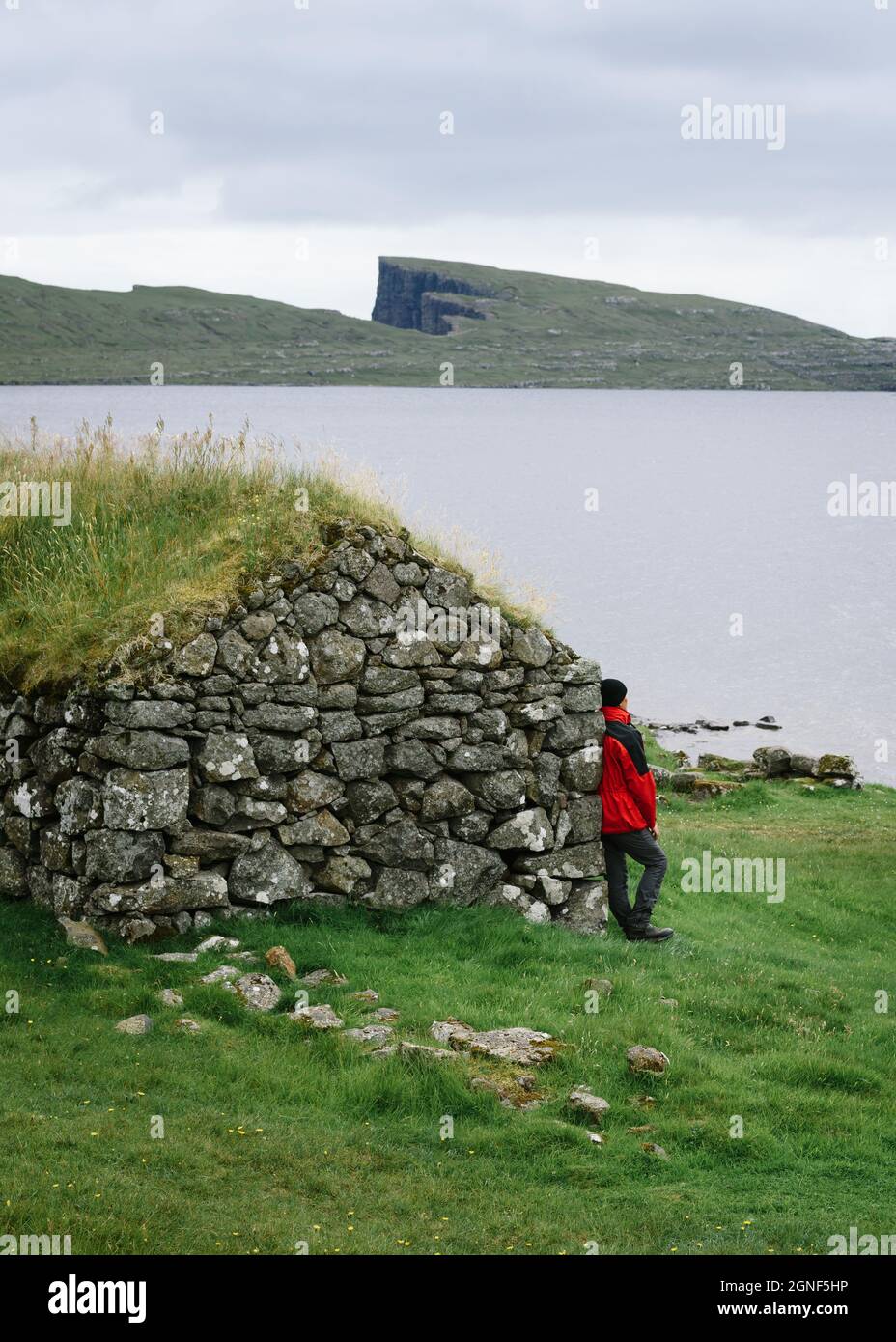 Homme solitaire près du lac. Paysage du nord par temps nuageux sur les îles Féroé Banque D'Images