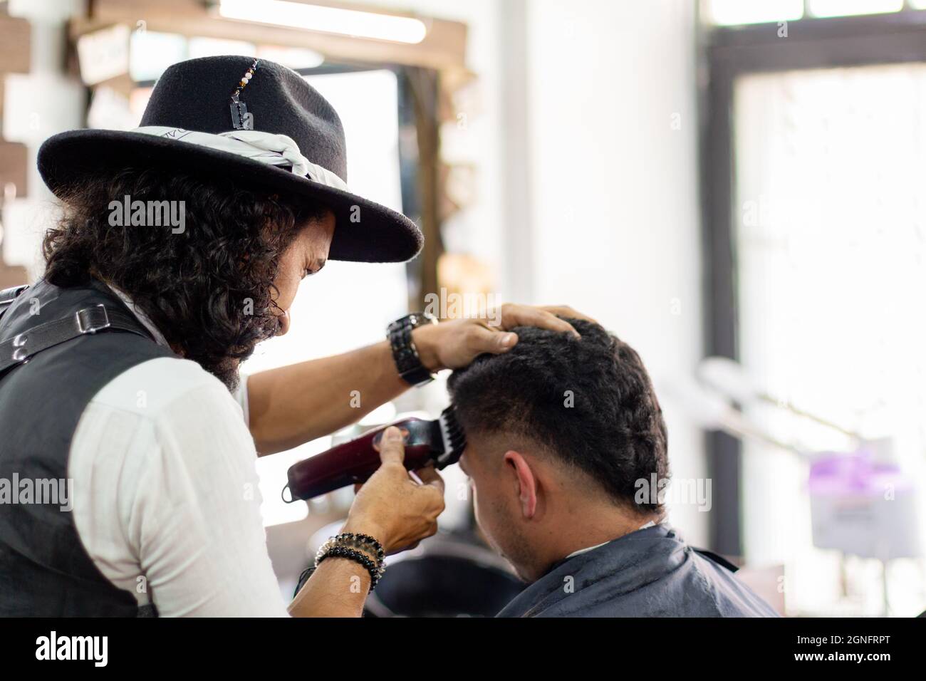 Coiffeur utilisant la tondeuse à cheveux sur le client. Styliste de la taille basse. Stimulation de la croissance des cheveux Banque D'Images