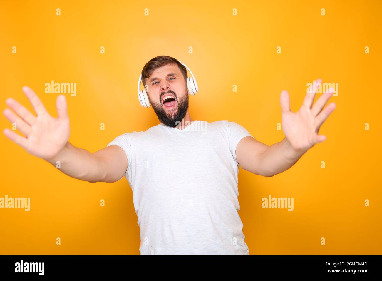 homme barbu dans un casque blanc chante fort et des gestes avec ses mains. Banque D'Images
