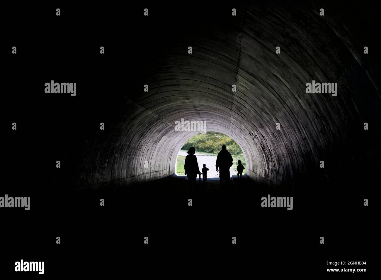 Silhouette de famille avec lumière au bout du tunnel dans un parc public Banque D'Images Silhouette de famille avec lumière au bout du tunnel dans un parc public Banque D'Images