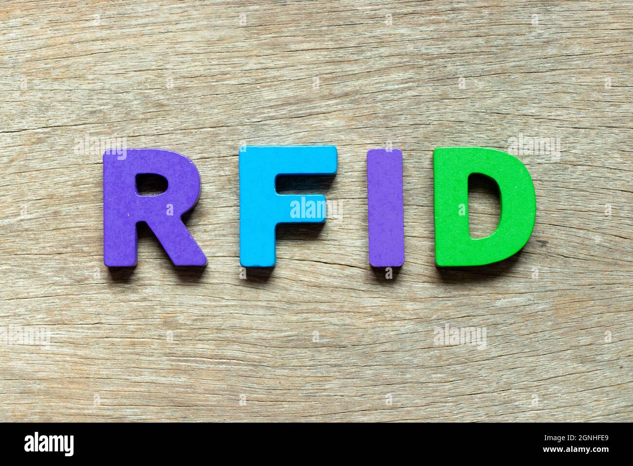 Lettre alphabétique de couleur dans le mot RFID (abréviation de l'identification par radiofréquence) sur fond de bois Banque D'Images