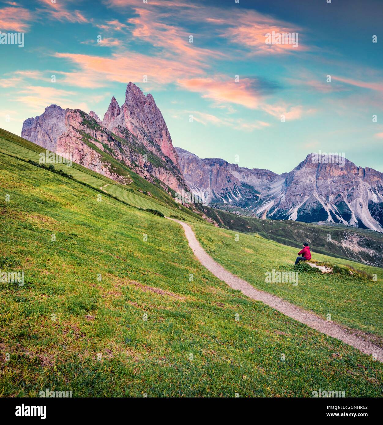 Le randonneur admire le magnifique lever du soleil avec le pic de Furchetta en arrière-plan. Belle scène estivale de la vallée de Funes. Une soirée fantastique à Puez Odle National Banque D'Images