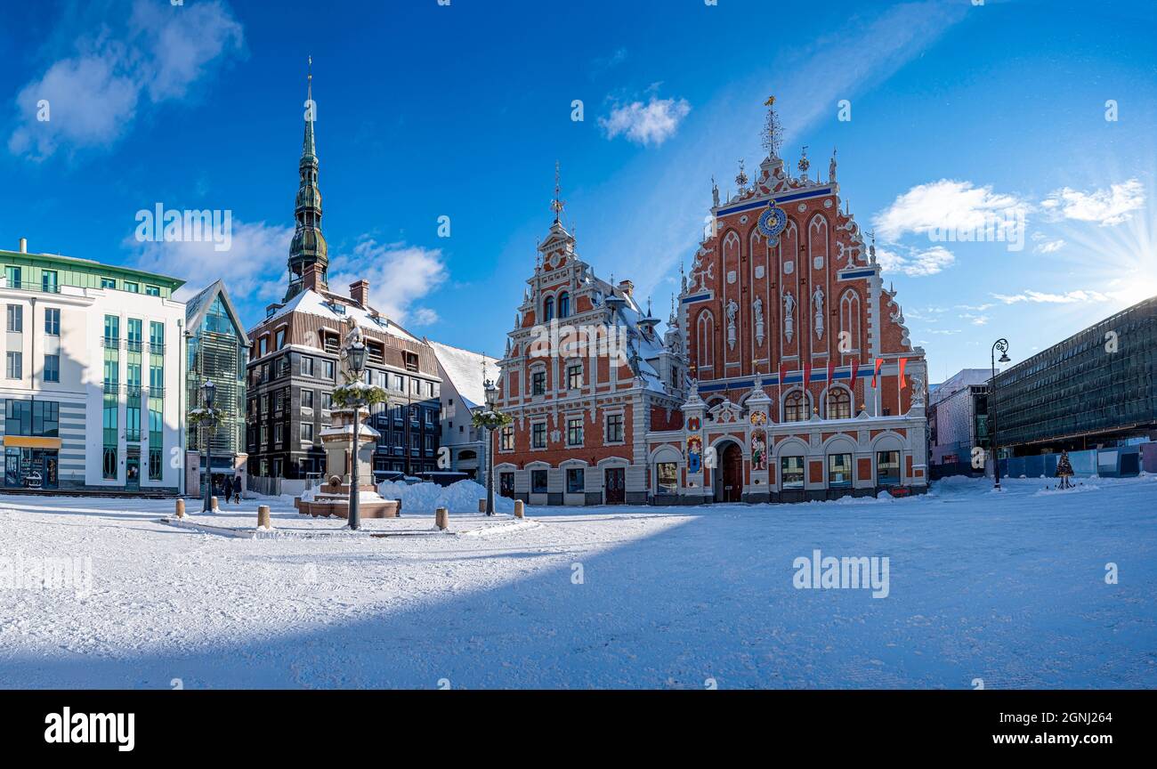 Place de l'hôtel de ville pendant la journée ensoleillée de neige en hiver à Riga, en Lettonie. Vue sur la maison enneigée des Blackheads et la statue de Roland dans la vieille ville de Riga. Banque D'Images