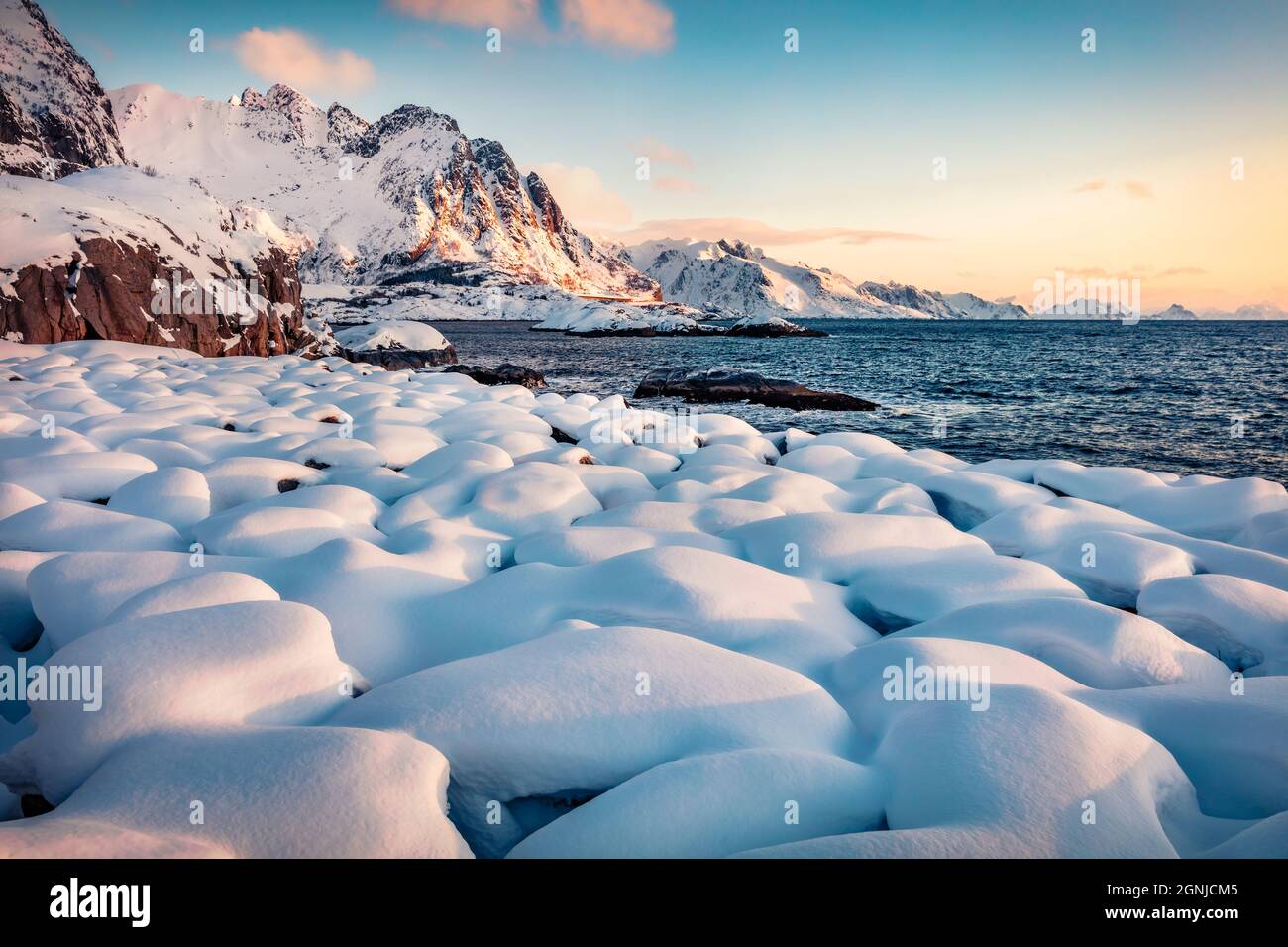 Magnifique lever de soleil d'hiver sur l'archipel des îles Lofoten. Pierres couvertes de neige fraîche sur les rives de la mer de Norvège. Magnifique scène matinale de Norvège, EUR Banque D'Images