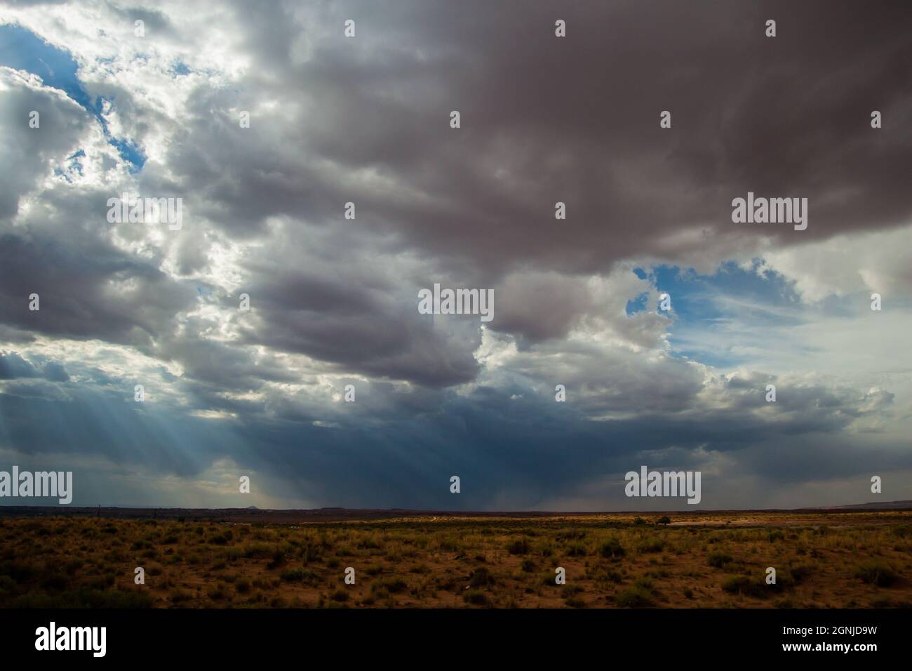 Magnifique paysage à couper le souffle avec des nuages gris foncé et blancs et un ciel bleu avec des rayons de lumière du soleil en même temps sur l'horizon de la plaine Banque D'Images
