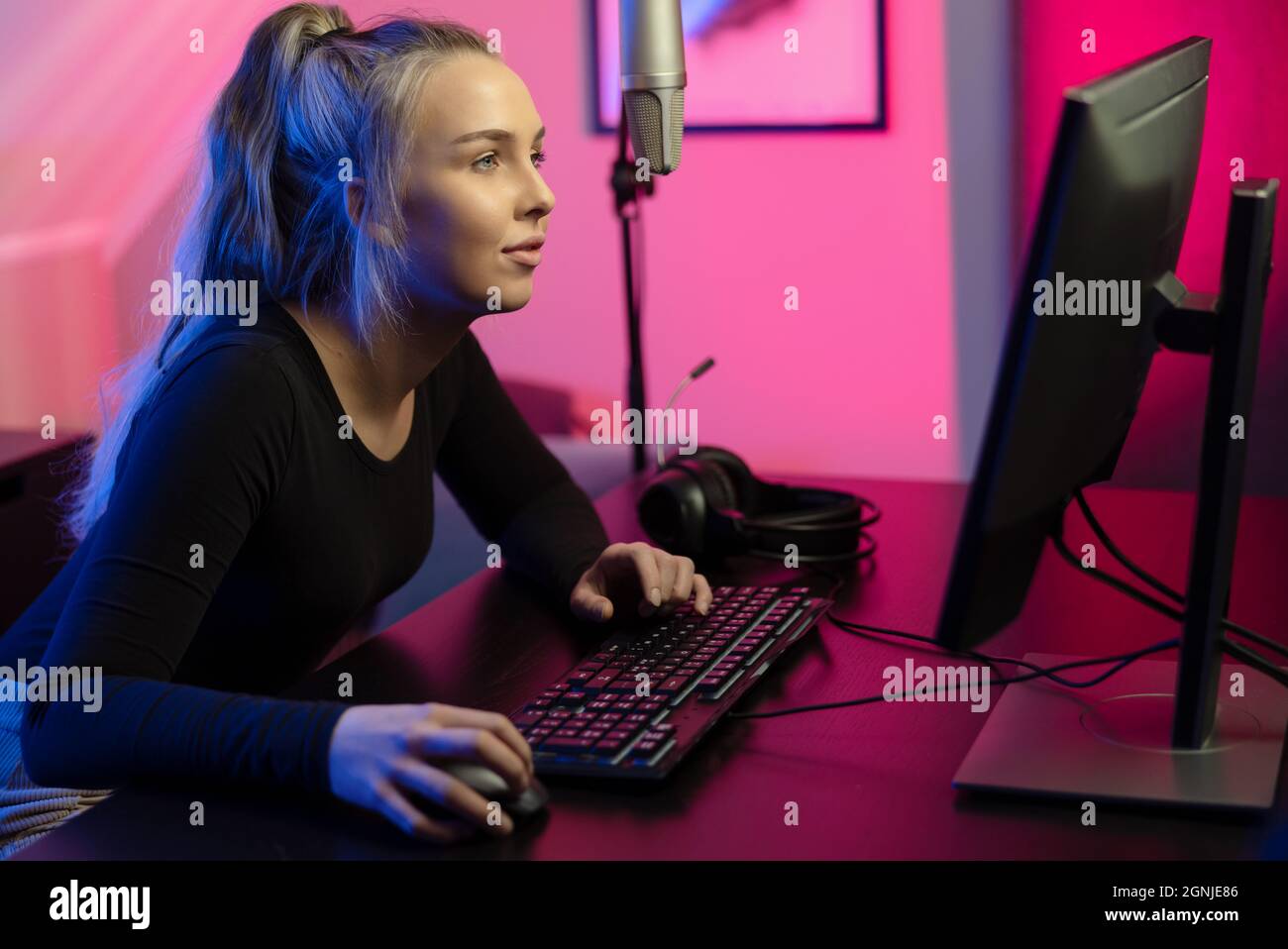 Mise au point et belle Blonde E-sport Gamer Girl avec casque jouer en ligne jeu vidéo sur PC Banque D'Images