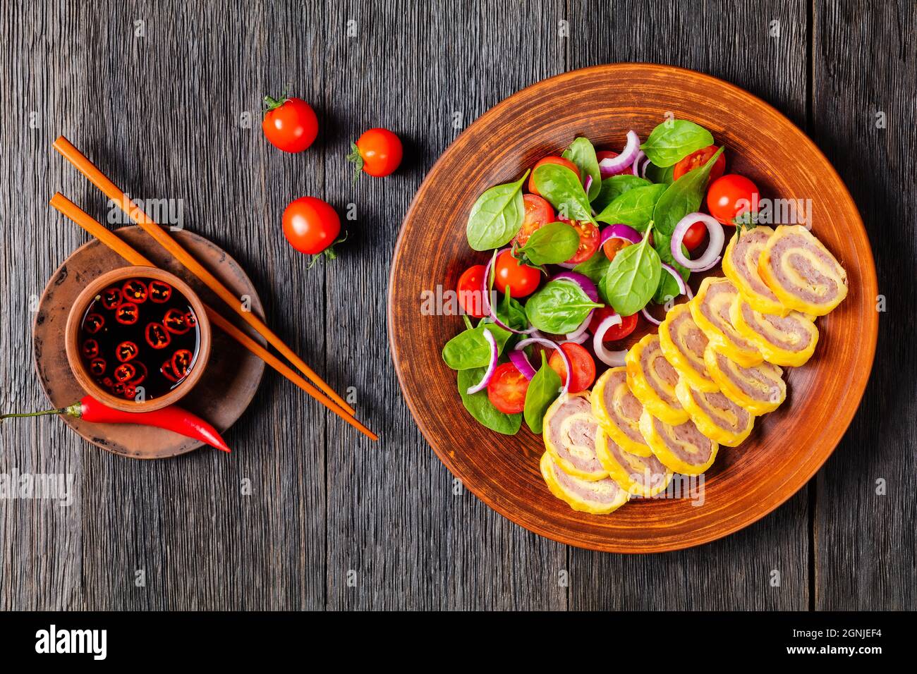 petit déjeuner au jambon et au fromage omelettes avec salade d'oignons rouges aux épinards frais sur une assiette rustique sur une table en bois avec sauce soja, vi horizontal Banque D'Images