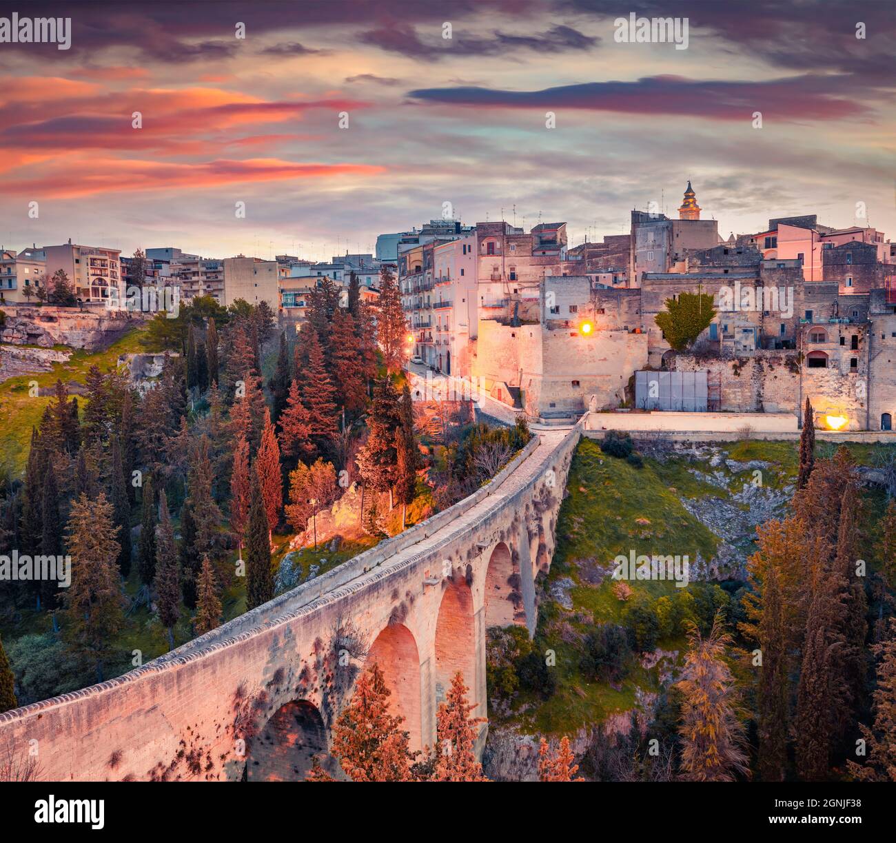 Viaduc ancien au-dessus d'un canyon profond. Lever de soleil de printemps coloré sur Gravina dans la ville de Puglia. Magnifique scène matinale d'Apulia, Italie, Europe. Concept de déplacement Banque D'Images