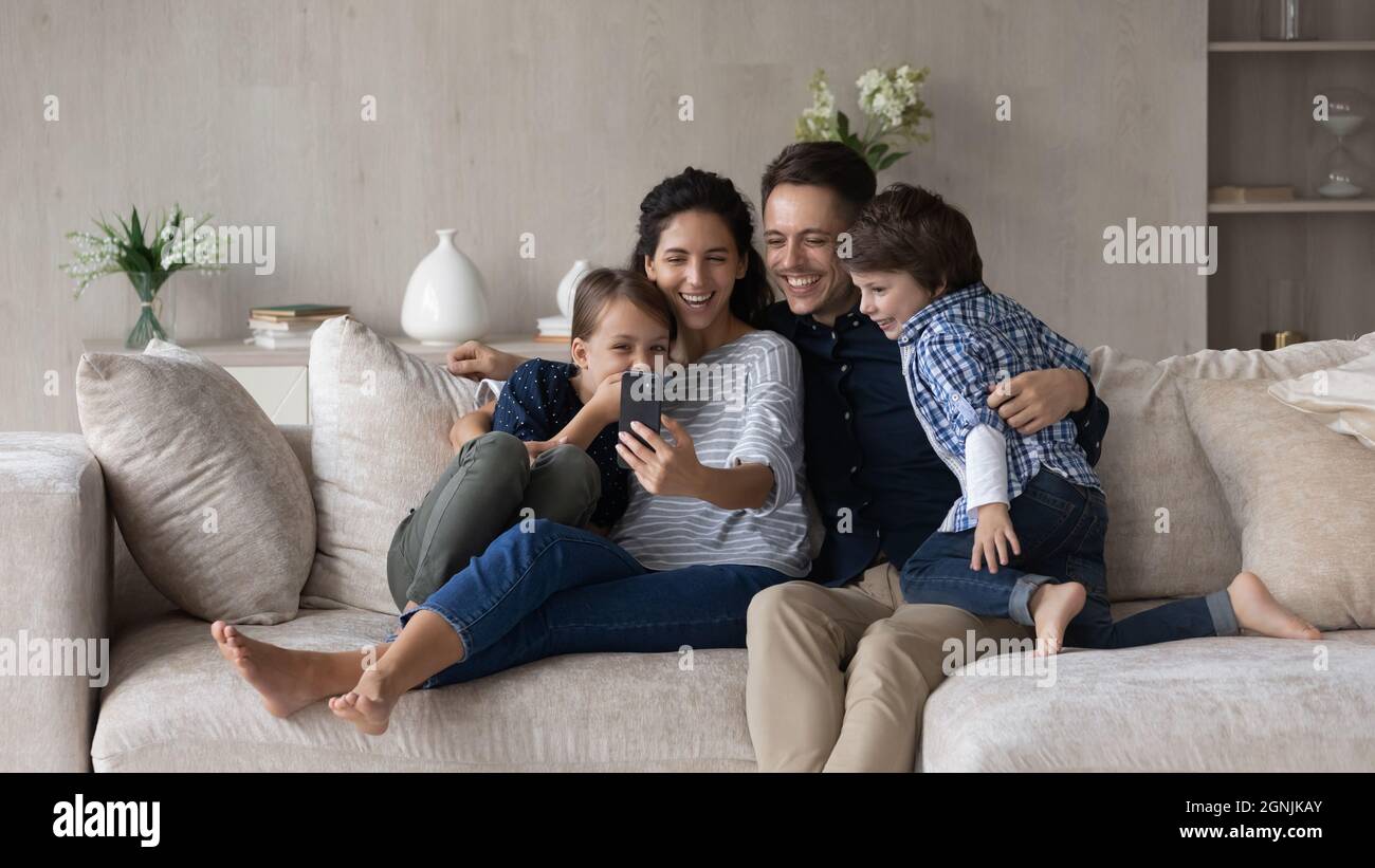 Famille sympathique et heureuse avec des enfants utilisant le téléphone portable. Banque D'Images