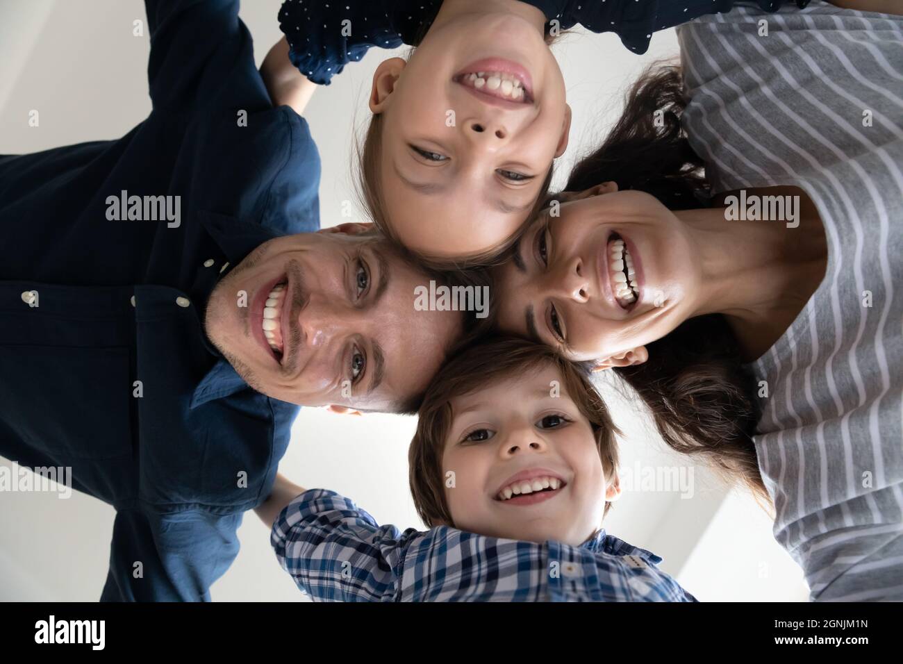 Joyeux jeune couple latin parents se joindre à la tête avec des enfants riant. Banque D'Images