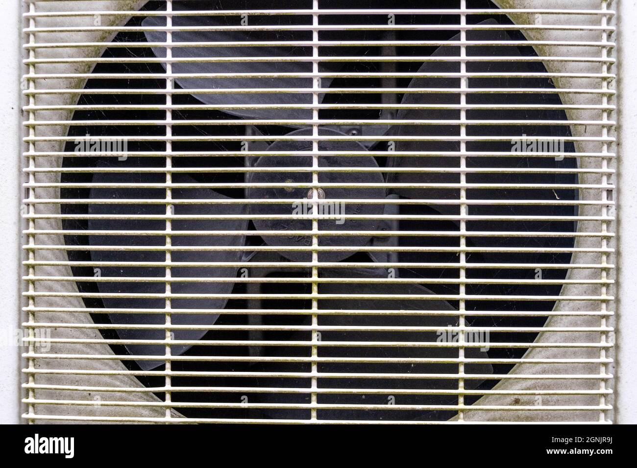 Gros plan d'Une unité de climatisation domestique et d'un ventilateur avec Un gril de sécurité en place et personne Banque D'Images