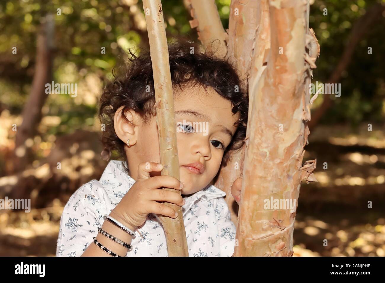 Portrait en gros plan d'un petit garçon hindou résidant en Inde qui se pose pour penser tristement et malheureux de poser la tête sur le tronc d'arbre Banque D'Images