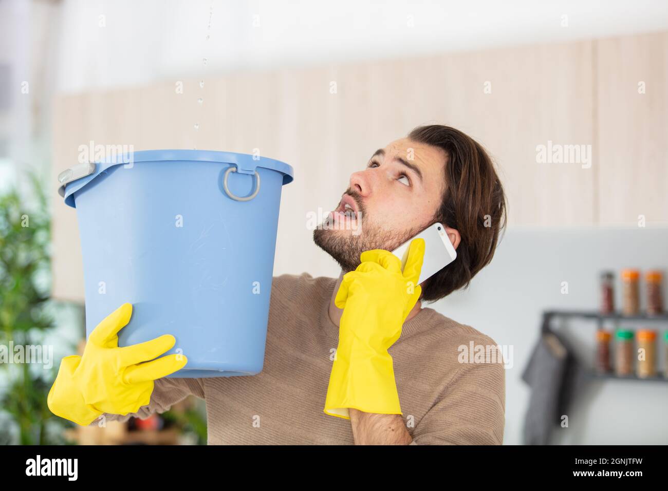 un homme inquiet qui a appelé le plombier alors que l'eau tombait au plafond Banque D'Images