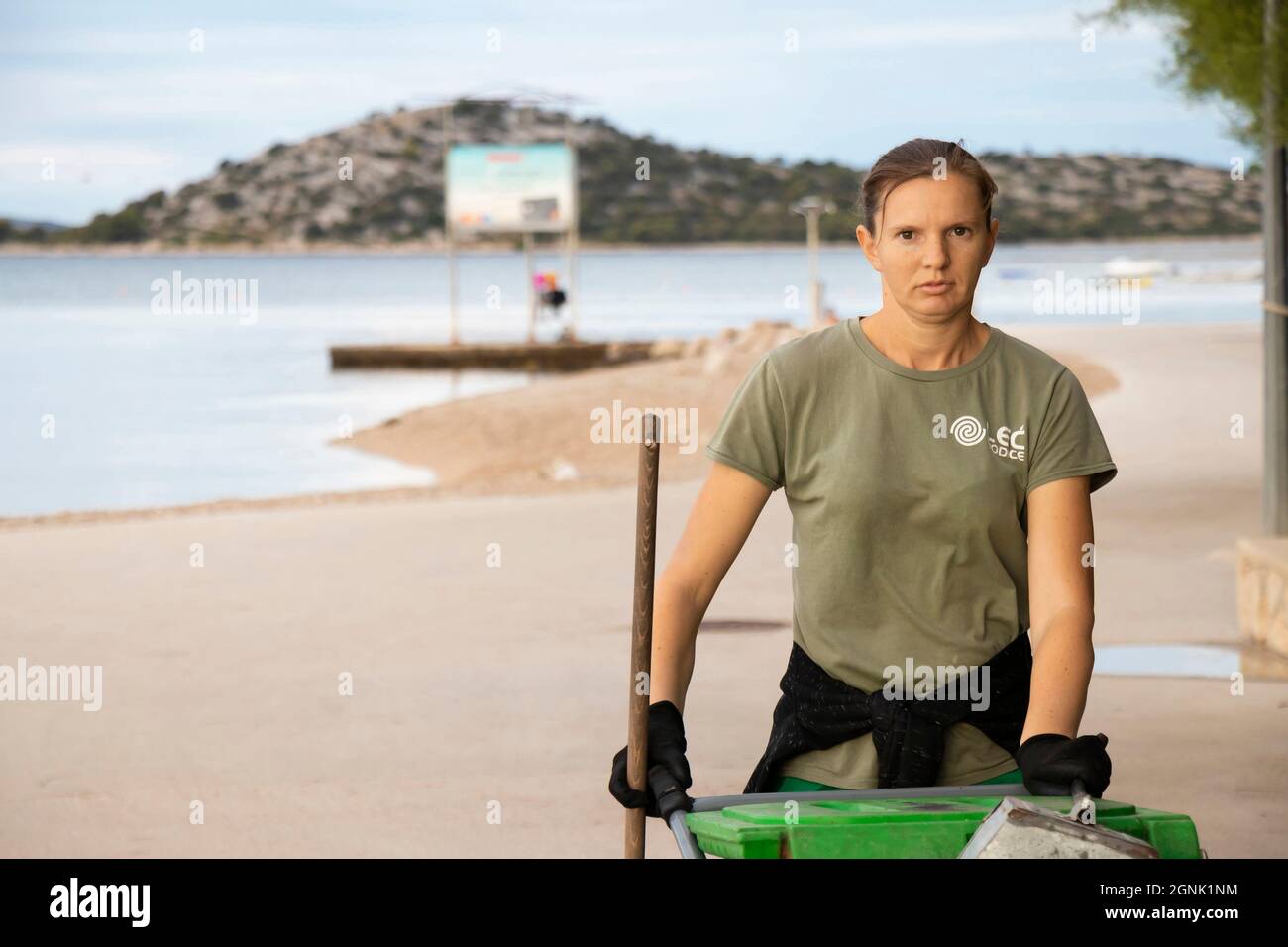 Vodice, Croatie - 28 août 2021: Jeune femme de ménage, travaillant pour le service de ville de Lec, sur son service de routine matinale de nettoyage de la plage Banque D'Images