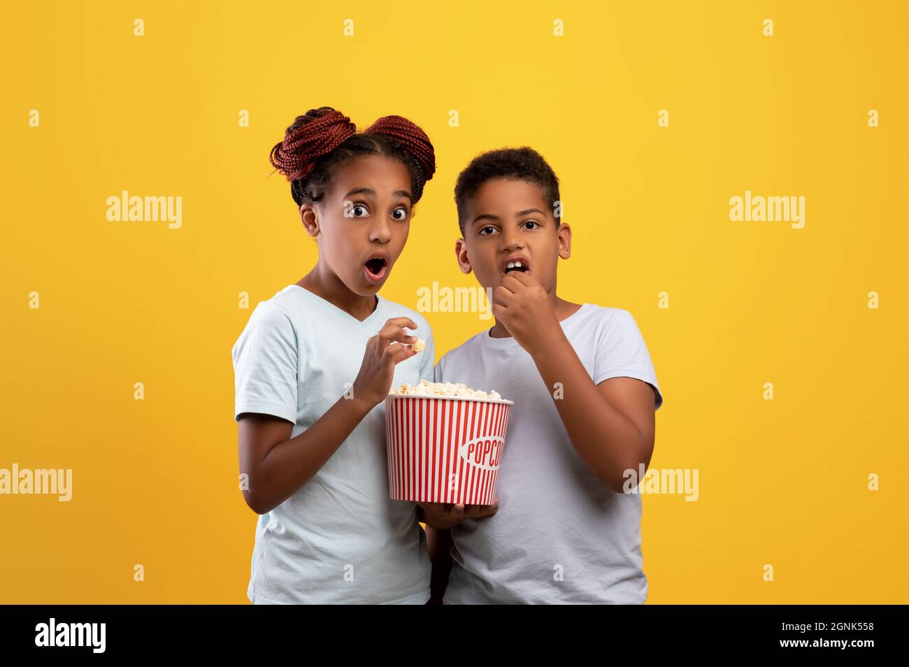 Enfants noirs émotionnels, garçon et fille mangeant du pop-corn, regardant le film Banque D'Images