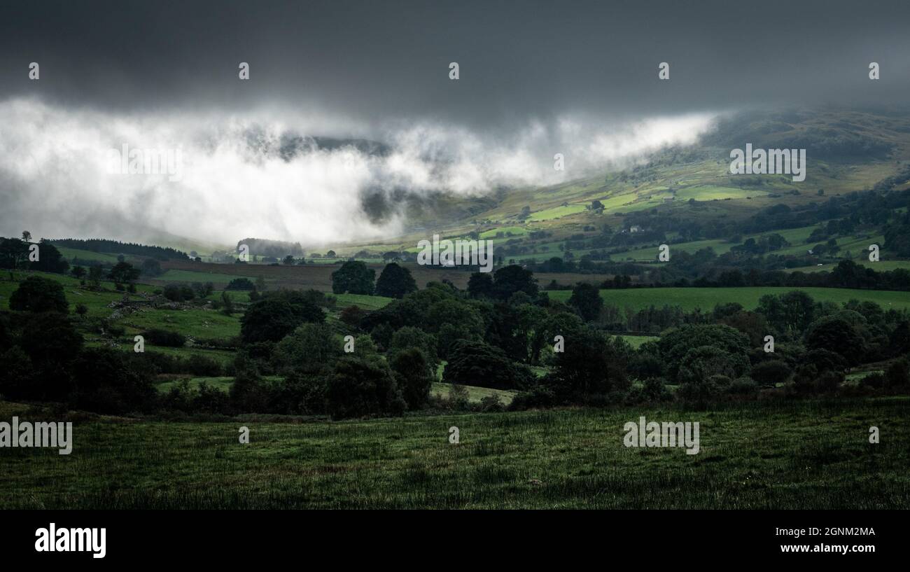 De spectaculaires nuages de tempête balayent le paysage verdoyant de la vallée galloise avec des collines ondulantes et des terres agricoles Banque D'Images