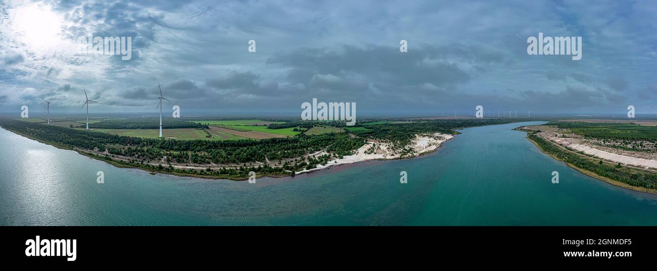 Vue aérienne sur un lac magnifique à côté d'un parc d'éoliennes dans un paysage coloré d'été. Banque D'Images