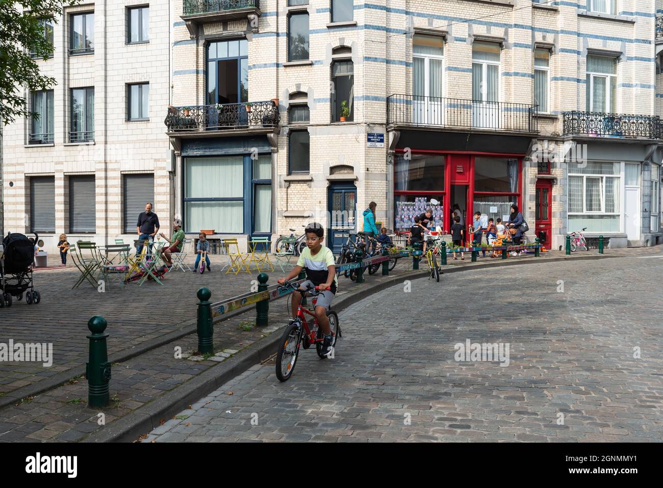Garçon conduisant un vélo sur une route pavée à la voiture gratuitement dimanche Banque D'Images