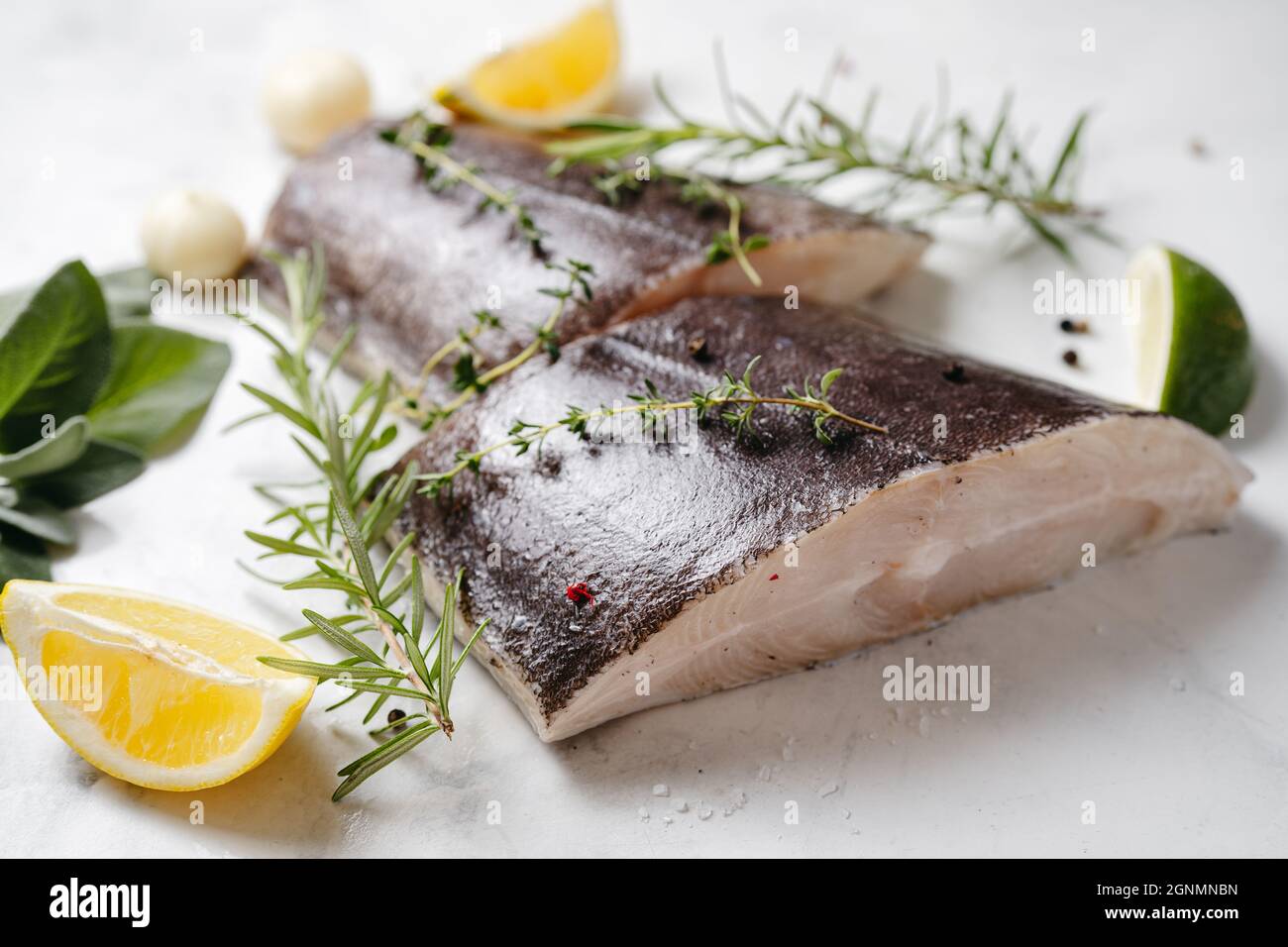Deux morceaux de poisson frais au flétan avec des herbes et du citron Banque D'Images