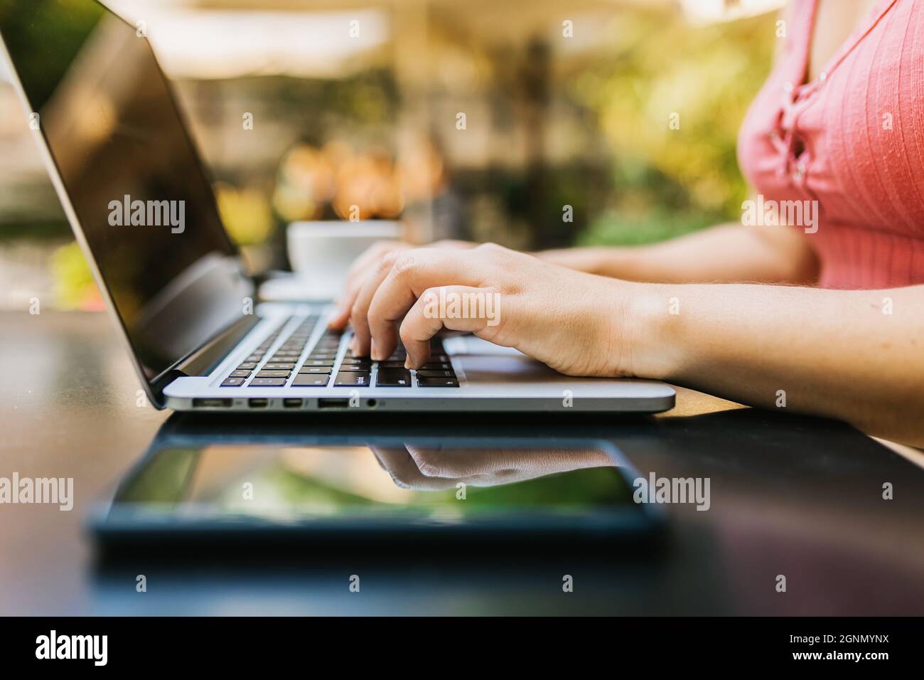 Vue latérale femme travaillant les mains sur ordinateur portable tout en étant assise sur la terrasse café Banque D'Images