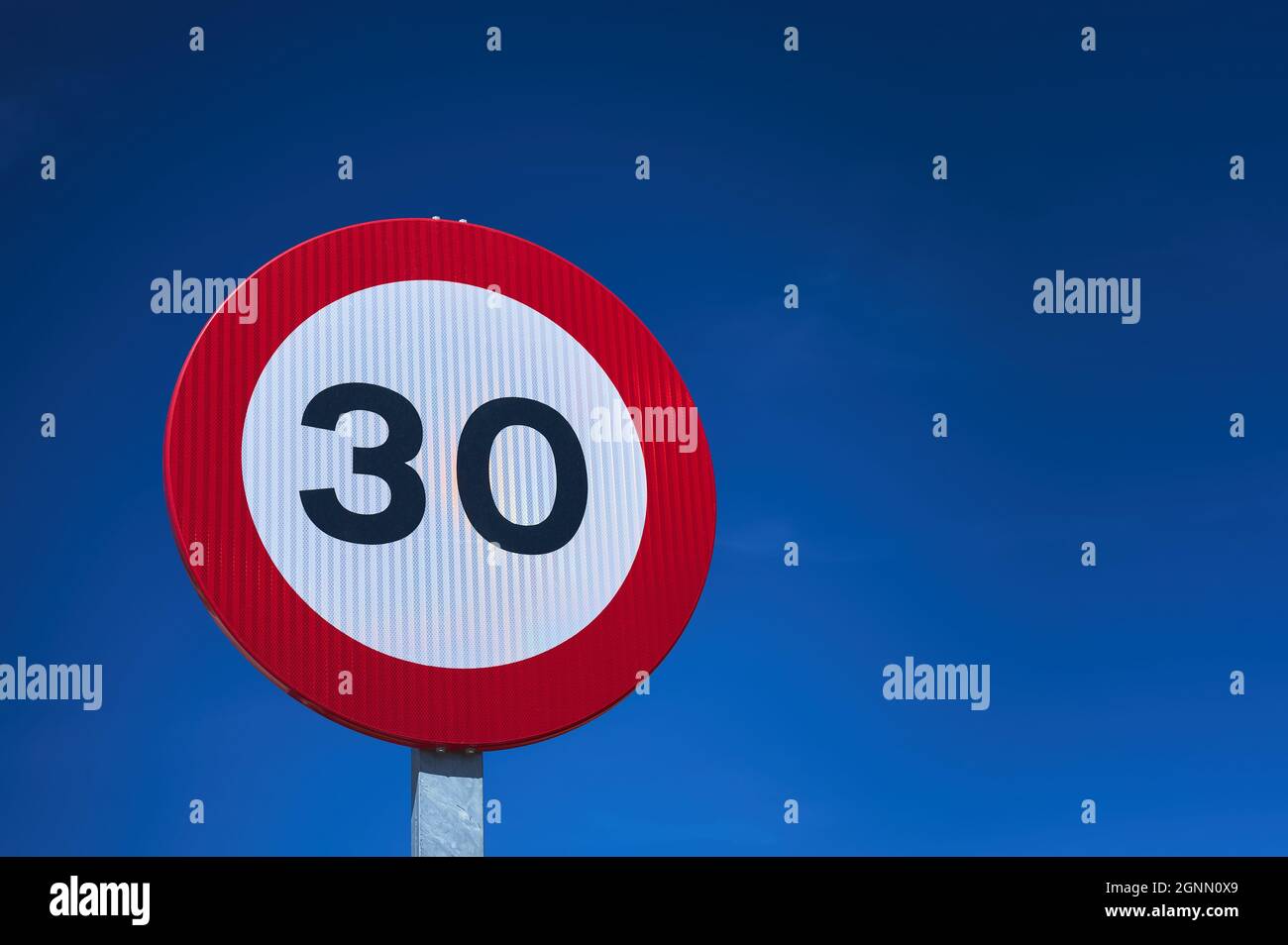 détail d'un panneau de signalisation routière de limite de vitesse de 30 km/h au-dessus d'un ciel bleu Banque D'Images