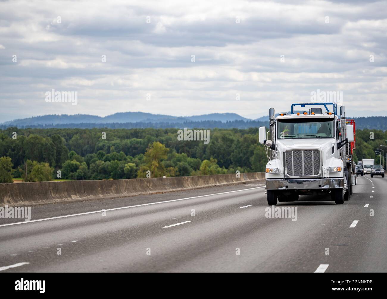 Capot de cabine de jour semi-camion blanc avec feux de toit supplémentaires et tuyaux d'échappement chromés transportant des marchandises sur une semi-remorque à plateau tournant sur le One wa Banque D'Images