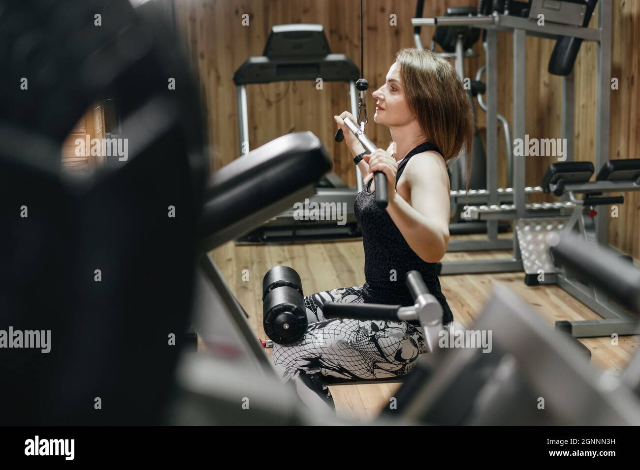 Belle femme sportive de soulever le poids dans la salle de gym sur la machine d'exercice. Femme d'âge moyen powerlifter avec tatouage. Corps solide et adapté, style de vie sain Banque D'Images