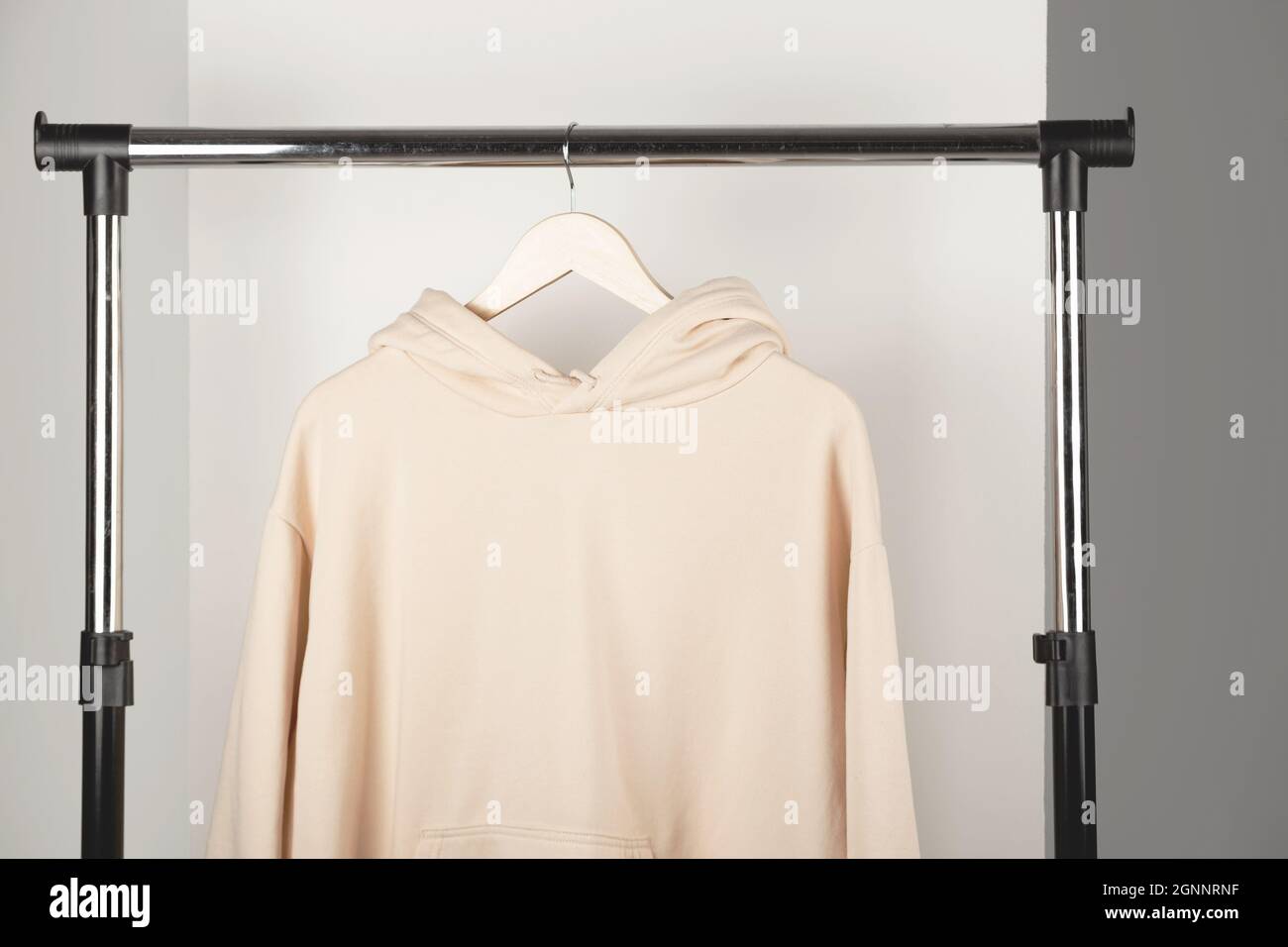 Sweat-shirt unisexe beige vierge qui se fond sur un cintre à vêtements. Sweat à capuche à l'intérieur minimaliste. Banque D'Images