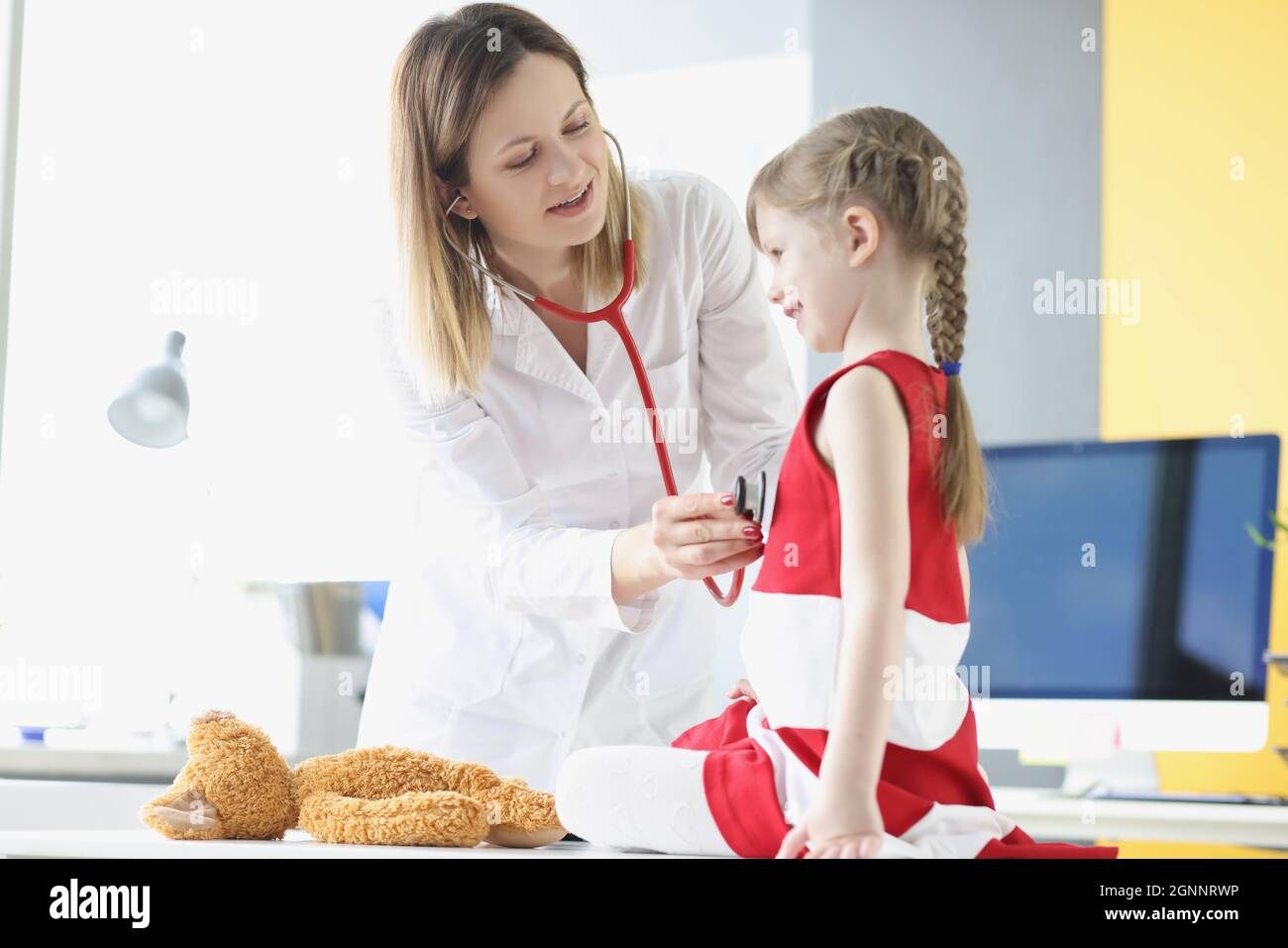 Le médecin pédiatre écoute la respiration et le battement de coeur avec le stéthoscope de la petite fille. Banque D'Images
