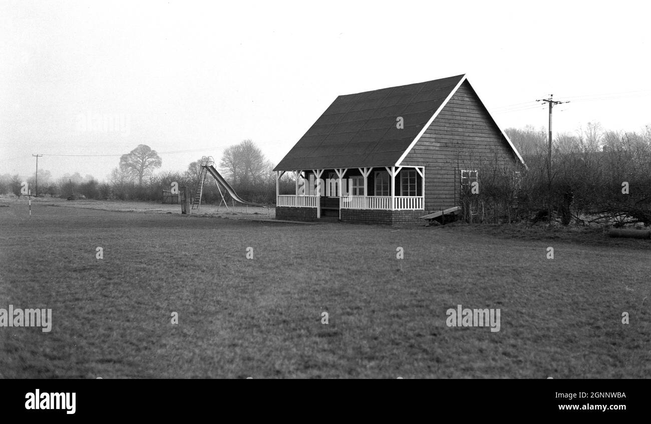 années 1950, vue historique et extérieure d'un pavillon sportif traditionnel de l'époque construit avec un cadre en bois et un toit haut.Construits avec une base en briques et une petite véranda couverte à l'avant, ces types de pavillons ont été vus dans de nombreux terrains de loisirs et de sports en Grande-Bretagne à ce moment, fournissant des vestiaires pour le cricket, le rugby et le football.À côté de ce pavillon à Witney, Oxford, Angleterre, Royaume-Uni, une aire de jeu de chlldrens, avec toboggan de médaille. Banque D'Images