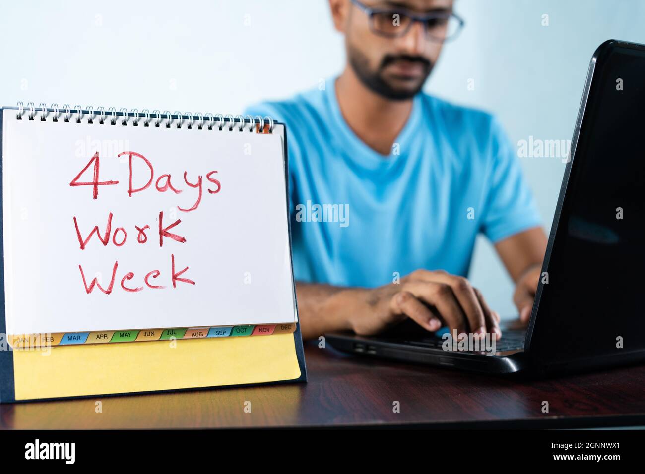 Se concentrer sur le calendrier, concept de quatre ou 4 jours de travail semaine montrant par jeune homme travaillant en arrière-plan et montre le calendrier. Banque D'Images