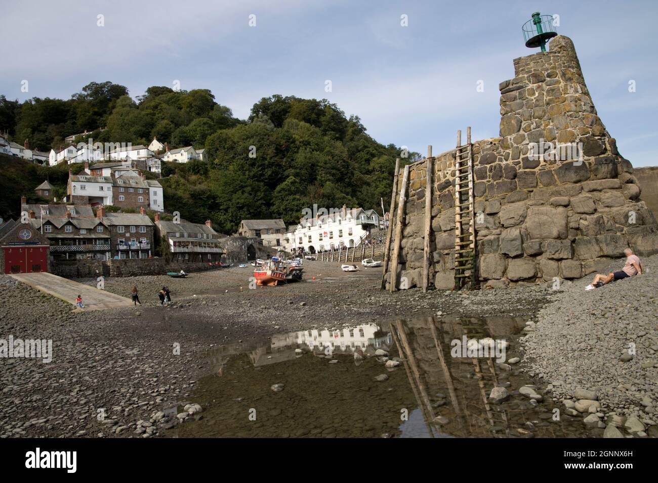Port de Clovelly à marée basse avec des bateaux de pêche amarrés et des poteaux d'amarrage sur le mur du port et l'hôtel Red Lion se reflète dans la piscine rocheuse North Devon Banque D'Images