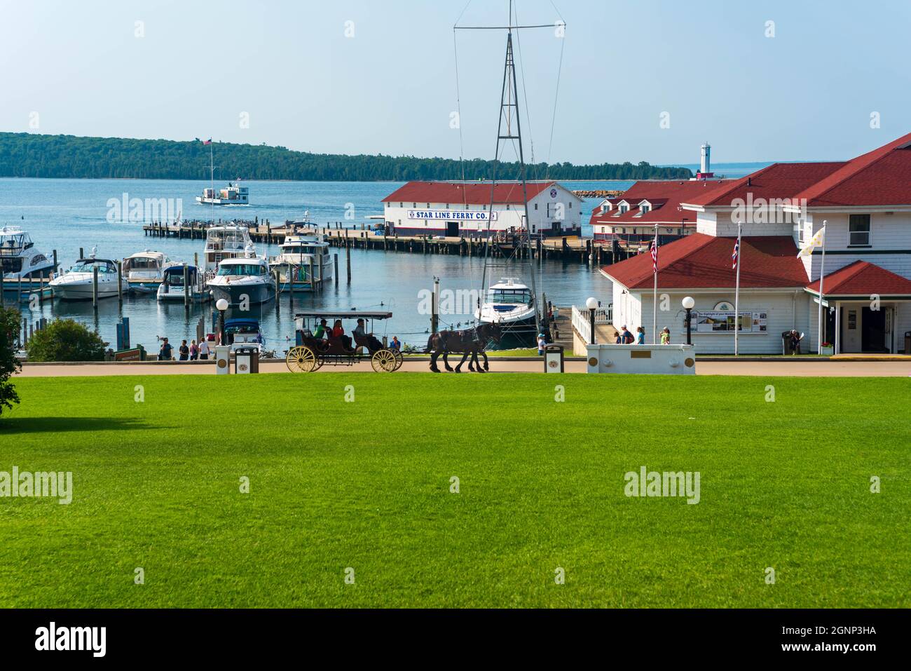 Mackinaw Island, MI - 14 juillet 2021 : cheval et buggy avec marina sur Mackinaw Island MI le 14 juillet 2021. Banque D'Images