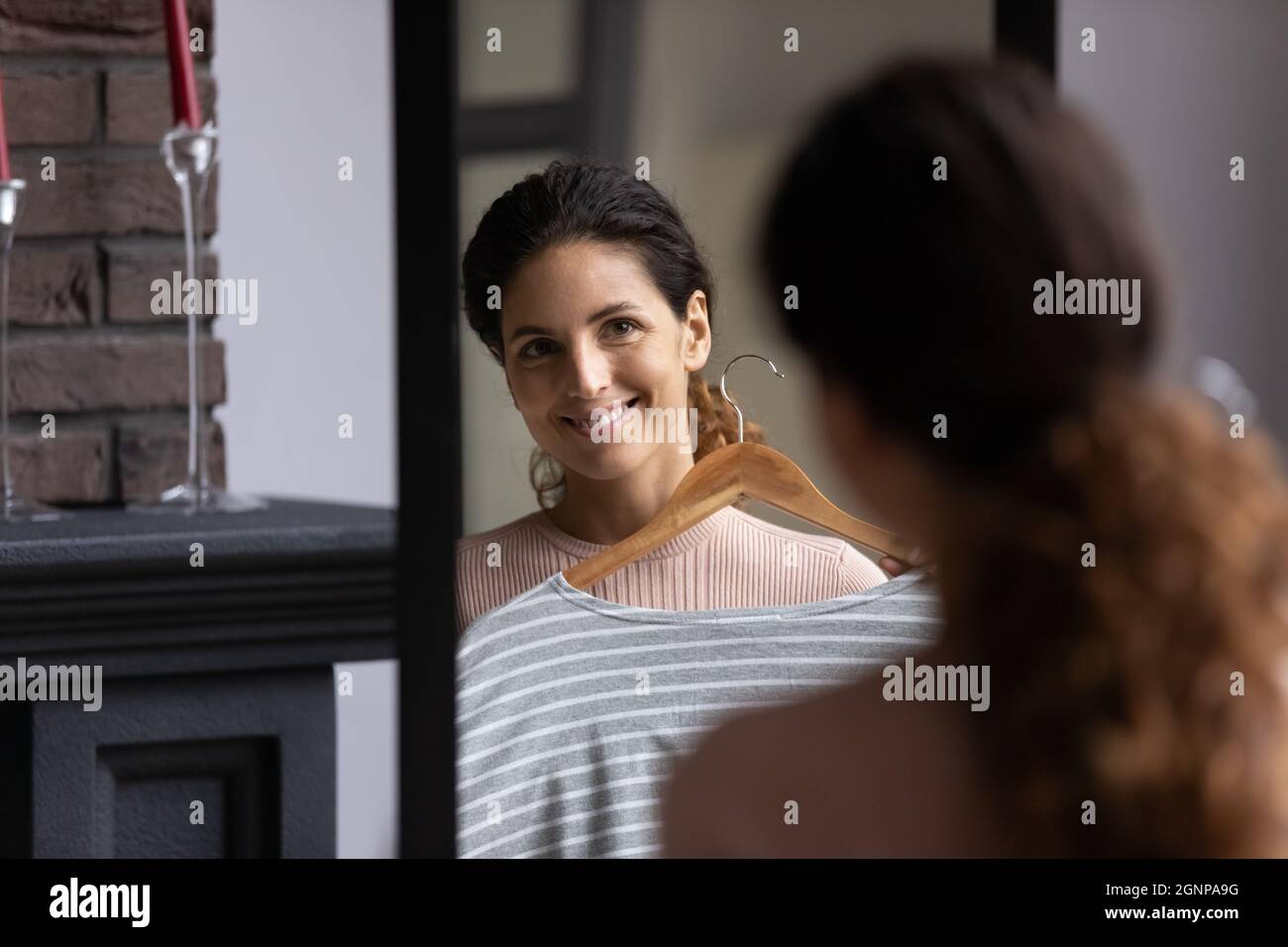 Une femme heureuse porte des vêtements qui regardent dans le miroir Banque D'Images