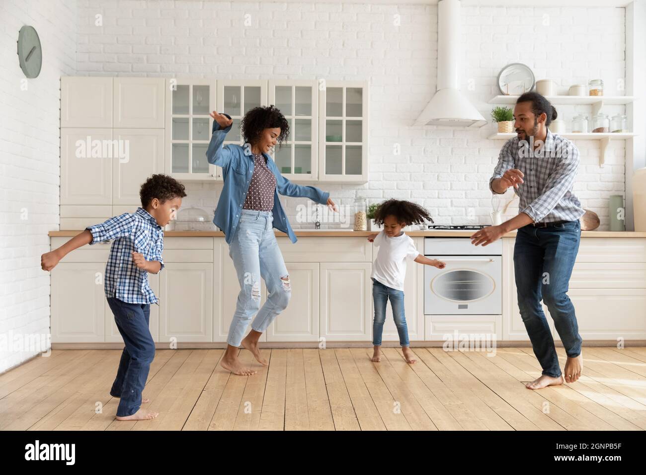 Bonne famille afro-américaine avec des enfants dansant dans la cuisine ensemble Banque D'Images