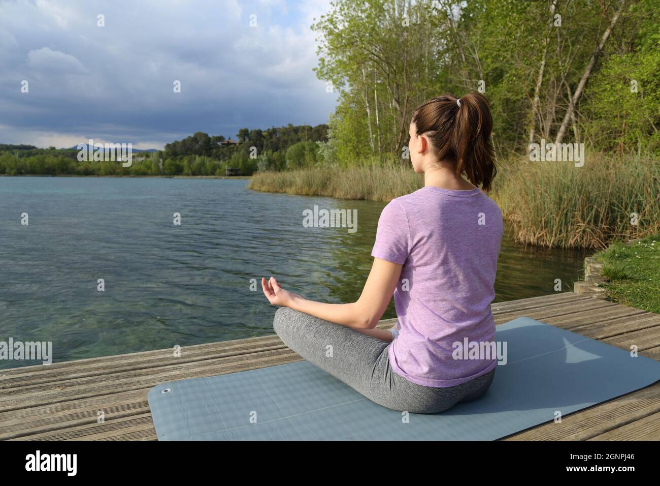 Yogi pratiquant l'exercice de yoga assis dans un quai de lac Banque D'Images