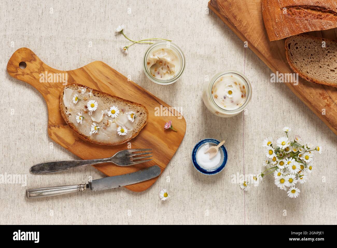 Délicieux gras d'oie avec du pain et des fleurs comestibles de pâquerette servis sur une planche à découper en bois. Vue de dessus. Banque D'Images