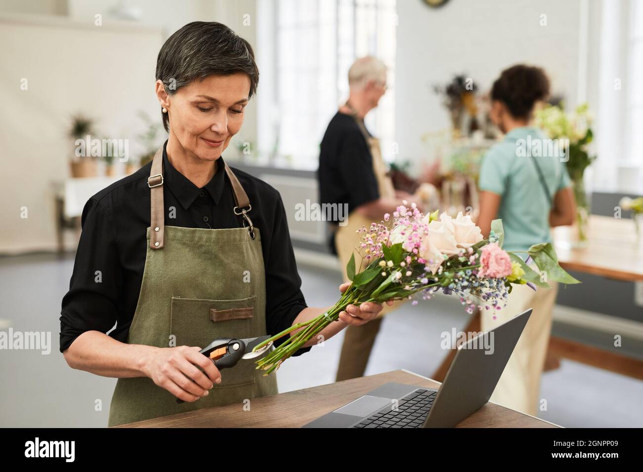 Portrait d'une femme élégante et mûre utilisant l'organisation de bouquets dans un fleuriste tout en gérant de petites affaires, l'espace de copie Banque D'Images