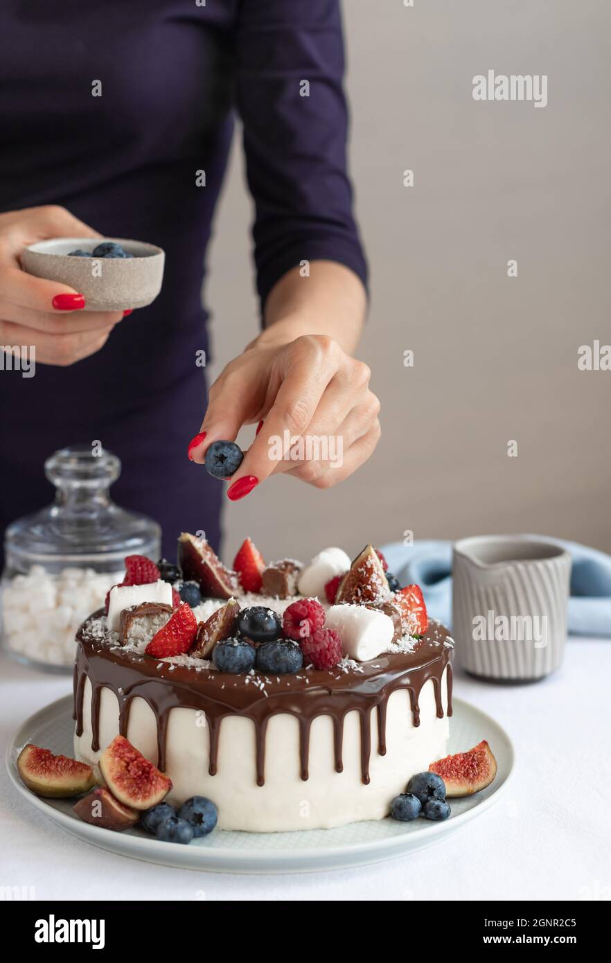 Confiseur décorant le gâteau blanc avec des baies fraîches Banque D'Images