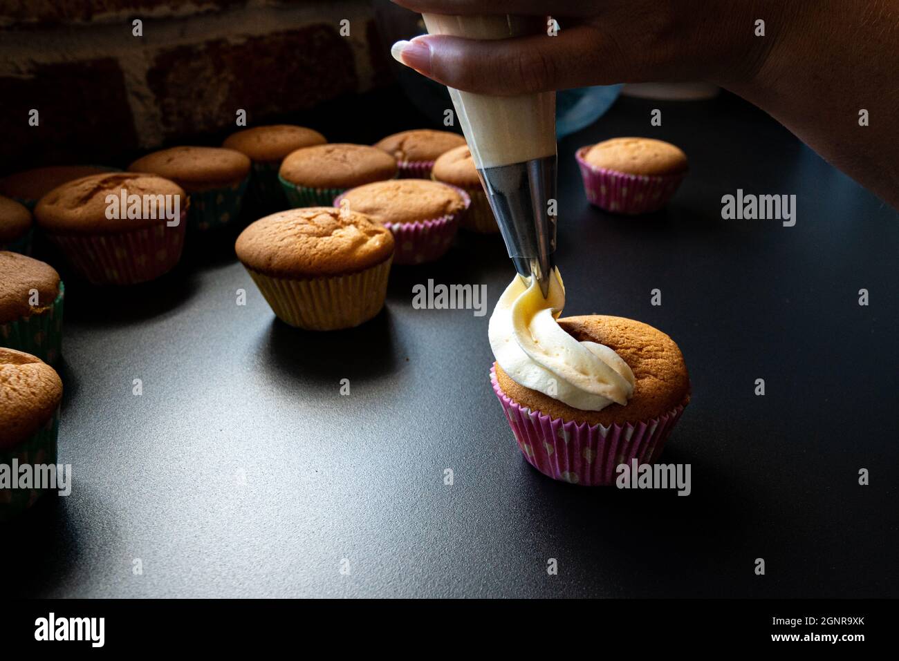 main montrant comment décorer des cupcakes avec de la crème de beurre Banque D'Images