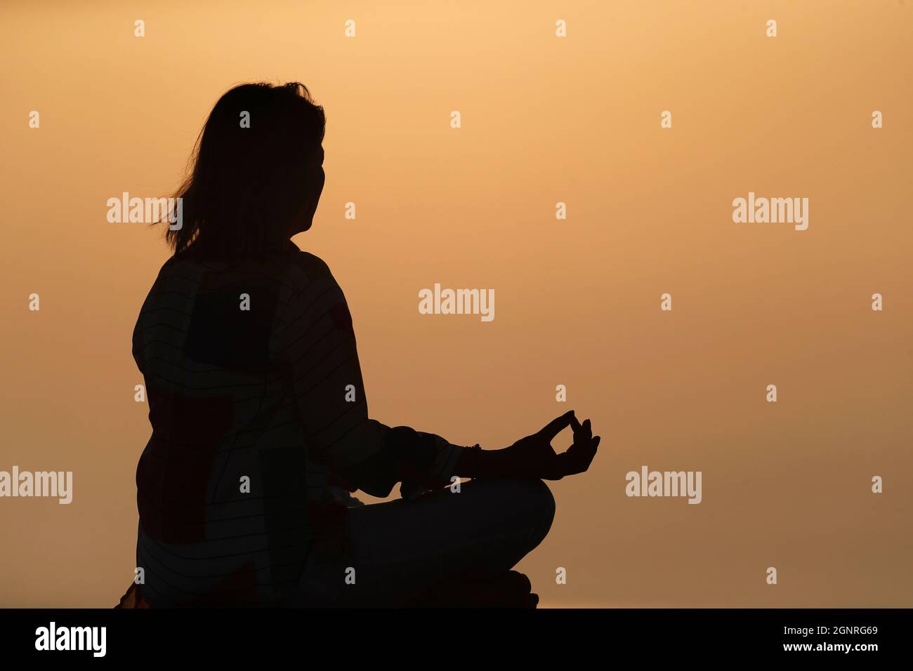 Femme pratiquant la pose de yoga et la méditation au coucher du soleil. Silence et relaxation concept. Banque D'Images