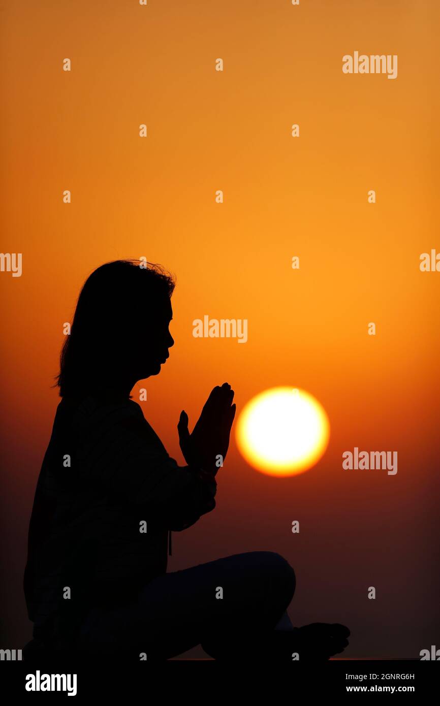 Femme pratiquant la pose de yoga et la méditation au coucher du soleil. Silence et relaxation concept. Banque D'Images