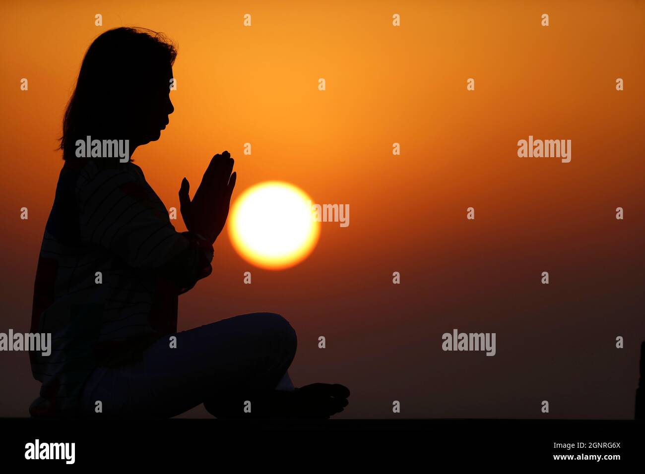 Femme pratiquant la pose de yoga et la méditation au coucher du soleil. Silence et relaxation concept. Banque D'Images