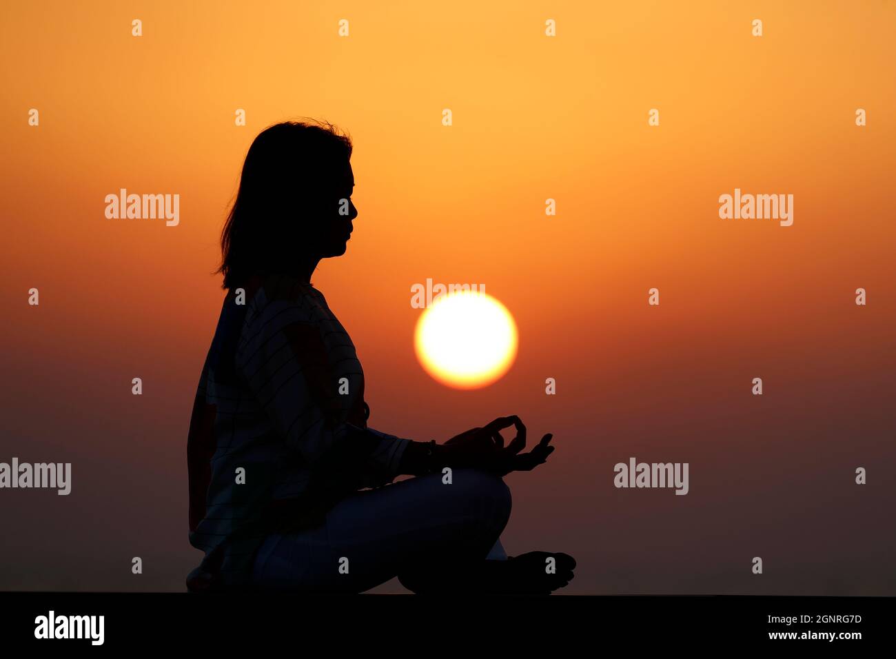 Femme pratiquant la pose de yoga et la méditation au coucher du soleil. Silence et relaxation concept. Banque D'Images