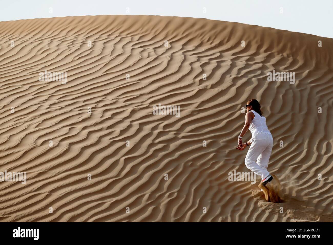 Femme laissant des empreintes de pas et allant jusqu'à la dune de sable du désert. Dubaï. Émirats arabes Unis. Banque D'Images