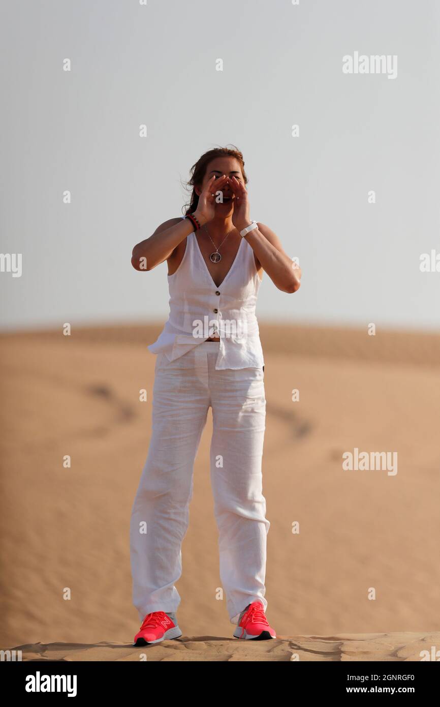 Femme criant dans le désert avec les mains sur la bouche. Dubaï. Émirats arabes Unis. Banque D'Images