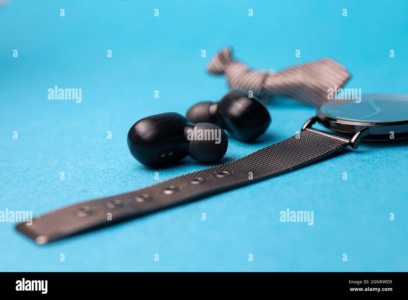 casque sans fil noir et montre sur fond bleu. Banque D'Images
