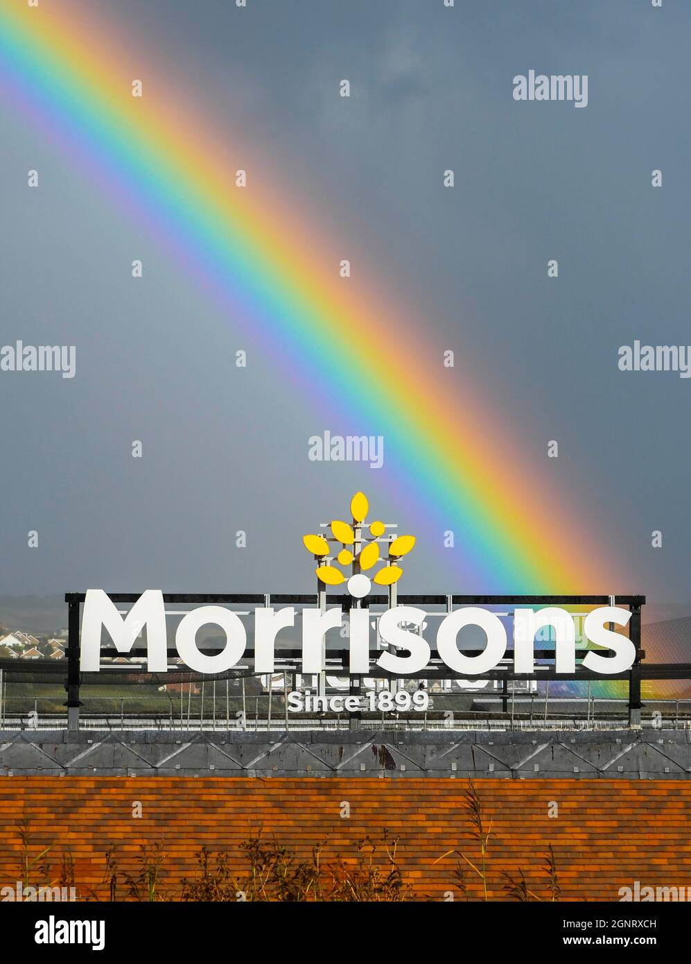 Weymouth, Dorset, Royaume-Uni. 27 septembre 2021. Météo Royaume-Uni. Un arc-en-ciel s'épare dans le ciel au-dessus d'un panneau de supermarché Morrisons à Weymouth à Dorset, le soleil se couche après une douche à forte pluie. Crédit photo : Graham Hunt/Alamy Live News Banque D'Images