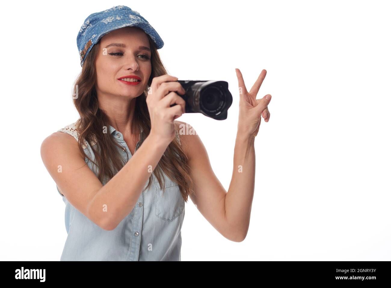 Contenu jeune touriste caucasien au panama chapeau montrant deux doigts tout en photographiant sur l'appareil photo Banque D'Images
