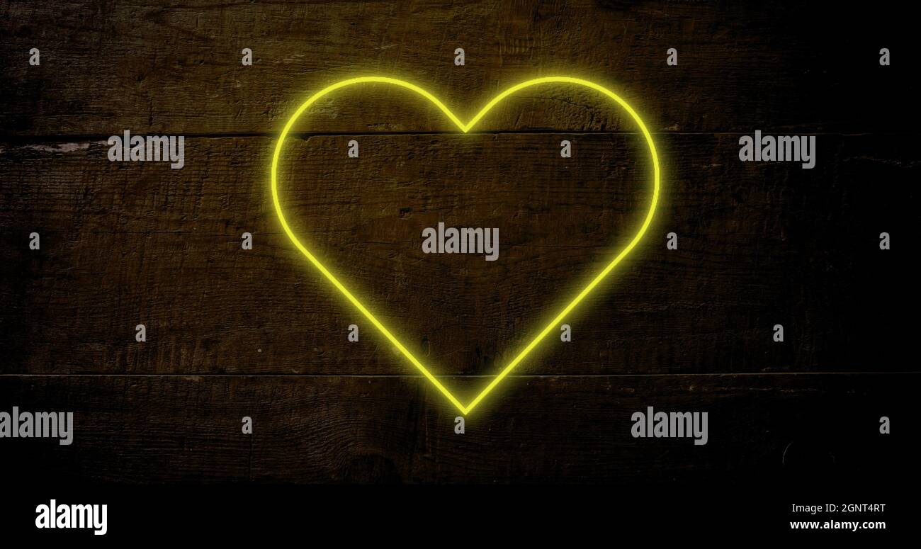 Image d'un cœur jaune fluo clignotant sur fond de bois sombre Banque D'Images